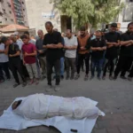 مشيعون يؤدون صلاة الجنازة أمام جثمان ملفوف بكفن في قطاع غزة
