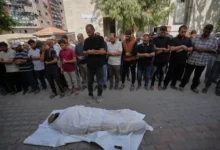 مشيعون يؤدون صلاة الجنازة أمام جثمان ملفوف بكفن في قطاع غزة