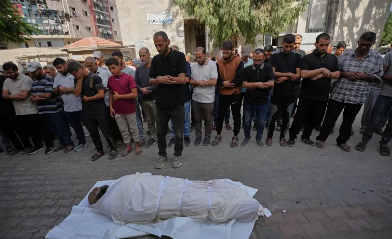 مشيعون يؤدون صلاة الجنازة أمام جثمان ملفوف بكفن في قطاع غزة