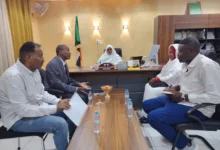 اجتماع رسمي حول طاولة تضم العلم السوداني