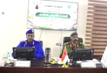 مسؤولان أمام منصة ولافتة في لقاء للشرطة