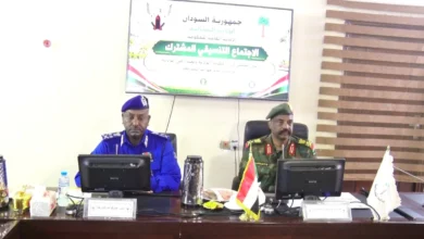 مسؤولان أمام منصة ولافتة في لقاء للشرطة