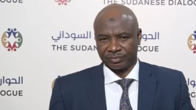 متحدث أمام خلفية تحمل شعار الحوار السوداني