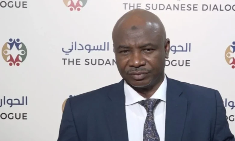 متحدث أمام خلفية تحمل شعار الحوار السوداني